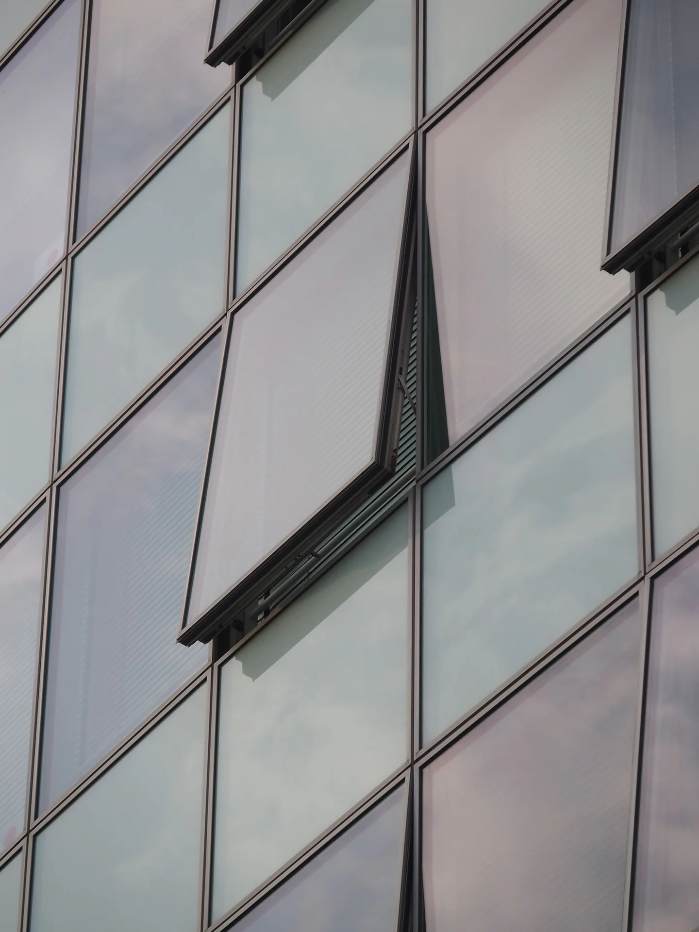 Fachada acristalada con ventanas practicables y reflejos del cielo