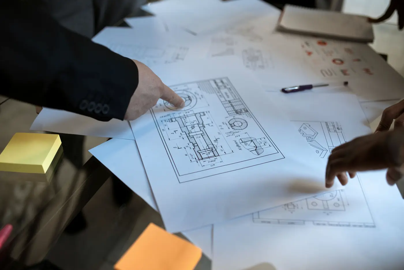 Manos de un equipo técnico revisando el detalle de un plano de proyecto